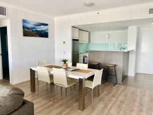 a kitchen and dining room with a table and chairs at Apartment 1102 | 11th Floor River & Stadium Views in Townsville