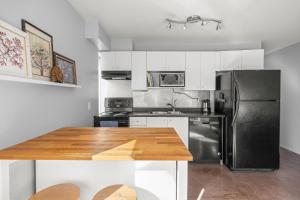 eine Küche mit einem schwarzen Kühlschrank und einem Holztisch in der Unterkunft Funky & Fun 1 Bedroom Condo Downtown Victoria, Free Parking! in Victoria