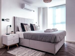 a white bedroom with a large bed and a window at Luxe Penthouse Retreat: With Free Parking! in Brentford