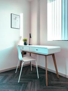 a desk in a room with a chair and a table at Luxe Penthouse Retreat: With Free Parking! in Brentford