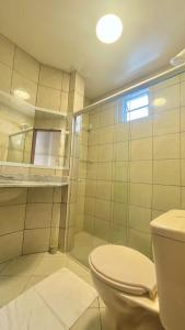 a bathroom with a toilet and a glass shower at Hospedaria Ilhéus 02 in Ilhéus