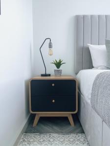 a nightstand with a lamp on it next to a bed at Luxe Penthouse Retreat: With Free Parking! in Brentford