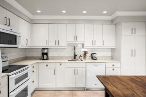 a white kitchen with white cabinets and a wooden table at Executive 2bed 3bath Townhome, James Bay/Dallas Rd. 2 Parking Spots, Hot Tub! in Victoria