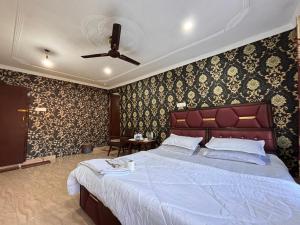 a bedroom with a large bed in a room with wallpaper at Hotel Crescent in Srinagar