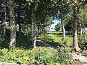 a path through a park with trees and flowers at Reestdal Cottage in De Wijk