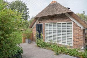 a brick house with a thatched roof and a garage at Reestdal Cottage in De Wijk