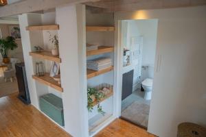 a room with a bathroom with a toilet and shelves at Reestdal Cottage in De Wijk