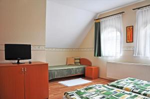 a small bedroom with a bed and a tv at Napsugár Vendégház in Tihany