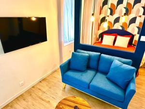 a living room with a blue couch and a tv at La vacancière - 308 in Rouen