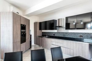 a kitchen with wooden cabinets and black appliances at Sea View 2 Bedroom Apartment in St. Paul's Bay