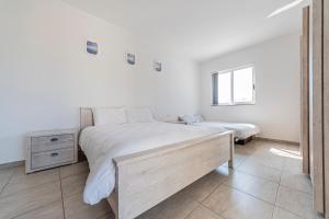 a white bedroom with two beds and a window at Sea View 2 Bedroom Apartment in St. Paul's Bay