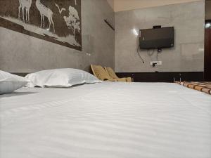 a large white bed in a room with a tv at Hillview Cottage in Kuttālam