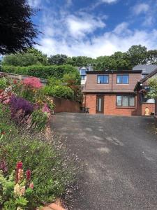 a house with a driveway and flowers in front of it at 1 bedroom self contained separate Annexe in Exeter in Ide