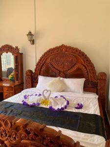 a bed with a wooden frame with a bouquet of flowers at Samnang Leap guesthouse in Senmonorom