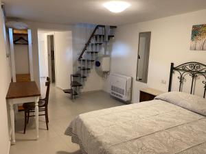 um quarto com uma cama, uma secretária e uma escadaria em Casa zia Vincenzina em Casalvecchio Siculo