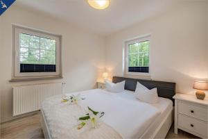ein Schlafzimmer mit einem weißen Bett mit Blumen darauf in der Unterkunft Villa Doris Whg 3 Flora in Heringsdorf