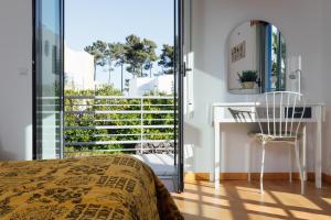 1 dormitorio con cama, escritorio y balcón en Villa Serena -your exclusive private swimming pool, en Palmela