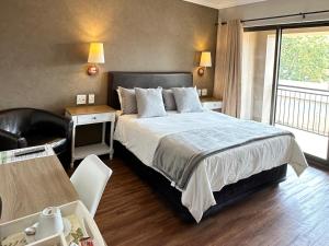 a bedroom with a large bed and a balcony at Cozy In Jozi in Edenvale