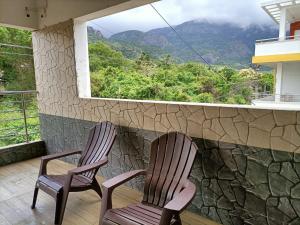 two chairs on a balcony with a view of a mountain at Hillview Cottage in Kuttālam