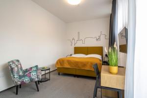 a bedroom with a bed and a chair and a table at Hotel VP1 in Ostrava