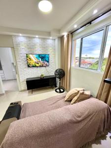 a bedroom with a bed and a tv on a brick wall at Ohanacaiçara apartamento próximo à praia do Sesc, completo e com Wi-Fi. in Bertioga
