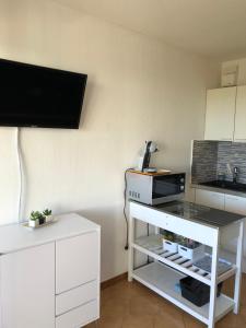 a kitchen with a white cabinet and a tv on a wall at Studio cabine climatisé in Sanary-sur-Mer