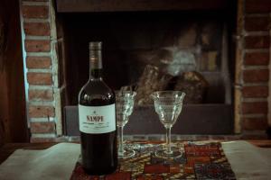 uma garrafa de vinho e dois copos numa mesa em El patio de Malek em Cosquín