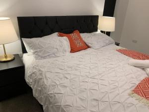 uma cama branca com duas almofadas com duas lâmpadas em Brand New Entire 4 Bed House Multiple Free Parking Early Check-in Late Check- Out Allowed em South Ockendon
