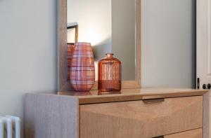 a wooden dresser with a mirror and a vase on it at Beautiful 2-Bedroom Apartment in Mayfair in London
