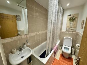 a bathroom with a sink and a toilet and a tub at Juli’s cosy home in London