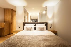um quarto com uma cama grande com lençóis brancos e almofadas em Deluxe Doppelzimmer mit Küchenzeile em Hilzingen