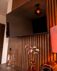 a vase with flowers on a table with a tv on a wall at Hotel Bom in Burgh Haamstede