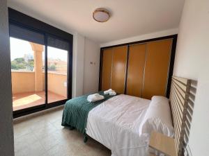 um quarto com uma cama e uma grande janela em Apartamento entero con terraza y piscina em Águilas