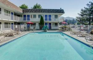 a swimming pool with chairs and a building at Motel 6-Grants Pass, OR in Grants Pass