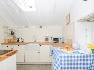 a kitchen with white cabinets and a table with a sink at Cobb Cottage in St Austell +16 photos