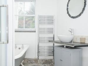 a white bathroom with a sink and a tub and a sink at Cobb Cottage in St Austell