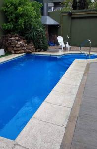 a blue swimming pool with a chair next to it at Hotel 24/11 in Mar del Plata