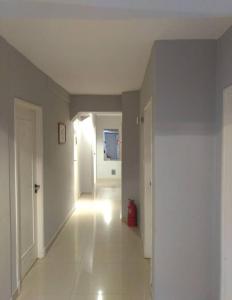 uma sala vazia com um corredor branco com um extintor de incêndio vermelho em Hotel 24/11 em Mar del Plata