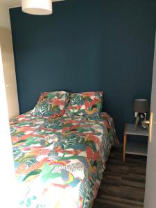 a bed with a colorful comforter in a bedroom at cottage chaleureux dans domaine privé in Signy-le-Petit
