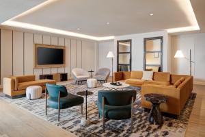 a living room with a couch and chairs and a tv at Sheraton Fort Worth Downtown Hotel in Fort Worth