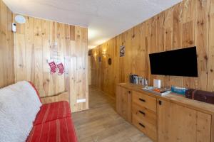 a room with wooden walls and a tv and a red couch at Arc 2000 appartement type chalet in Bourg-Saint-Maurice