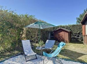 a patio with two chairs and an umbrella at Le chalet de Blonville in Blonville-sur-Mer