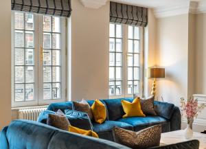 a blue couch in a living room with windows at Beautiful 2-Bedroom Apartment in Mayfair in London