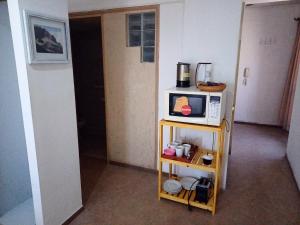 um pequeno quarto com um micro-ondas numa prateleira em GARCIA INN MZA con desayuno seco em Mendoza