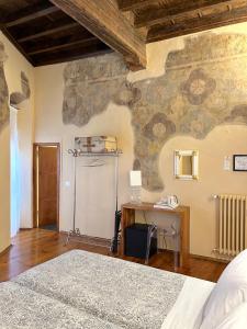 um quarto com uma parede de pedra, uma cama e uma secretária. em Guicciardini 24 em Florença