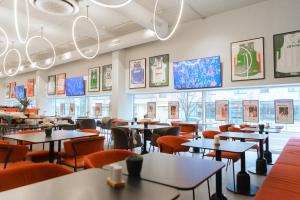 a restaurant with tables and chairs and windows at IBIS Styles Kaunas Centre in Kaunas