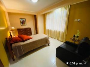 una camera con un letto e una sedia e una finestra di Albreth - Hotel Bungalows a Huaraz