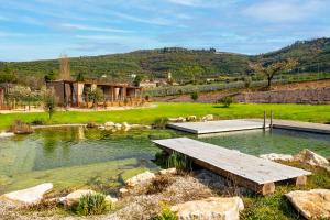 a pool of water with a wooden bench in a field at Val di Venere Glamp House in Santa Maria in Stelle