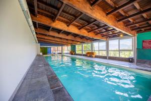 an indoor pool with blue water and wooden ceilings at Résidence Château des Magnans by Nevesol in Jausiers