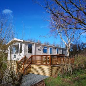 uma casa móvel com um grande deque no pátio em Red Squirrel Holiday Home in the Countryside, 10 mins to Lligwy Beach em Llandyfrydog